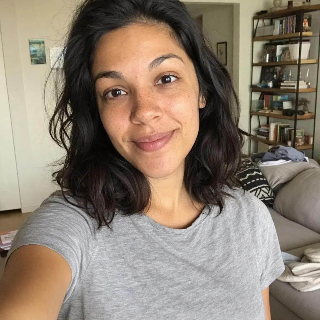 Casual phone selfie of a woman in a grey t-shirt in a living room